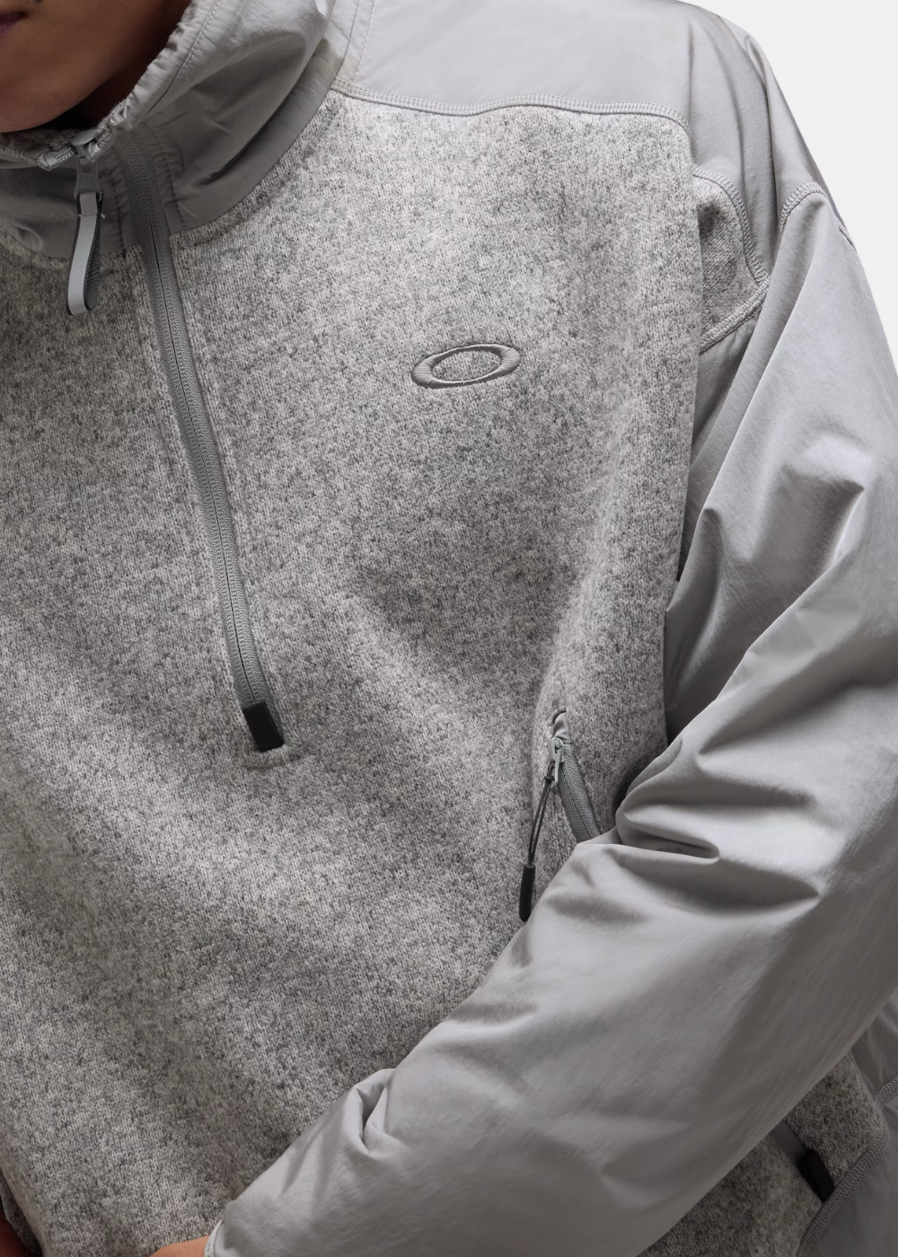 Gros plan sur la fermeture zippée et le logo Ellipse Oakley brodé sur le sweat Polartec gris