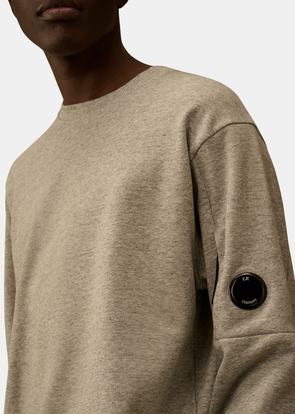Gros plan sur le détail verre Lens noir C.P. Company sur la manche gauche du sweat gris chiné