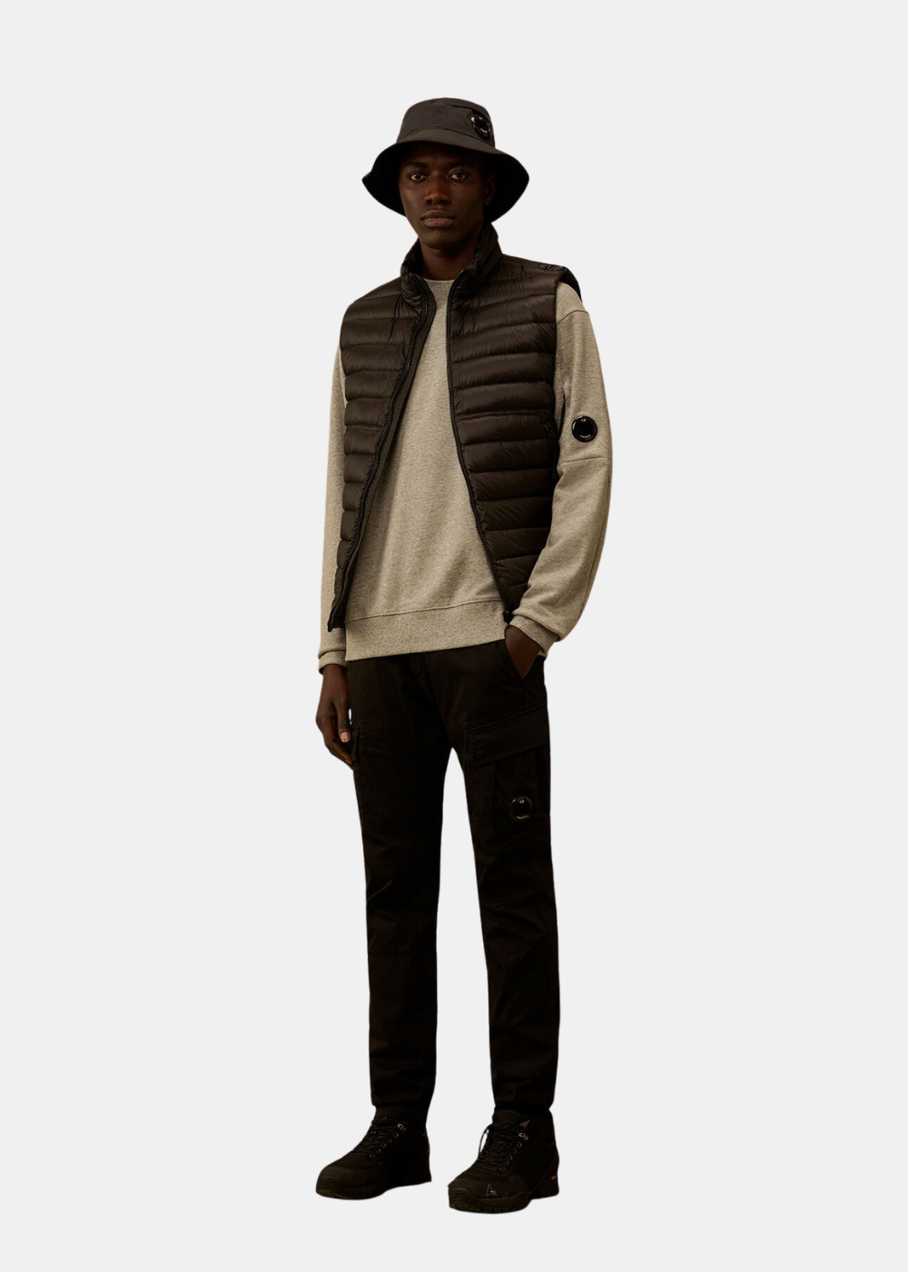 Silhouette complète portée du sweat C.P. Company gris chiné avec doudoune sans manches noire et bob assorti