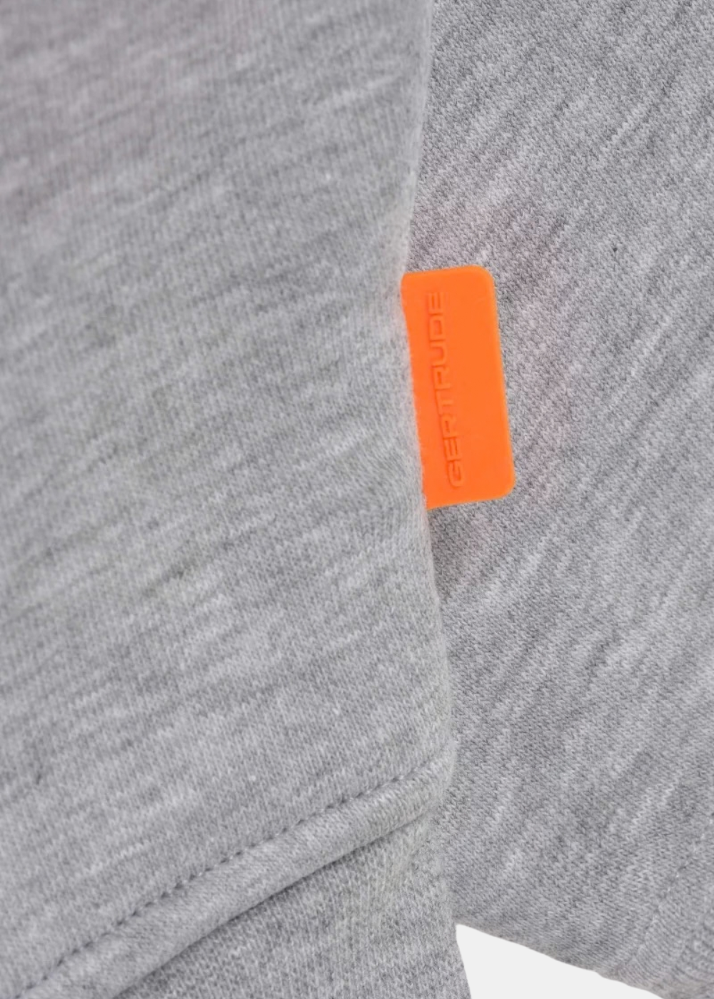 Gros plan sur l'étiquette en silicone orange Gertrude sur le côté du sweat gris