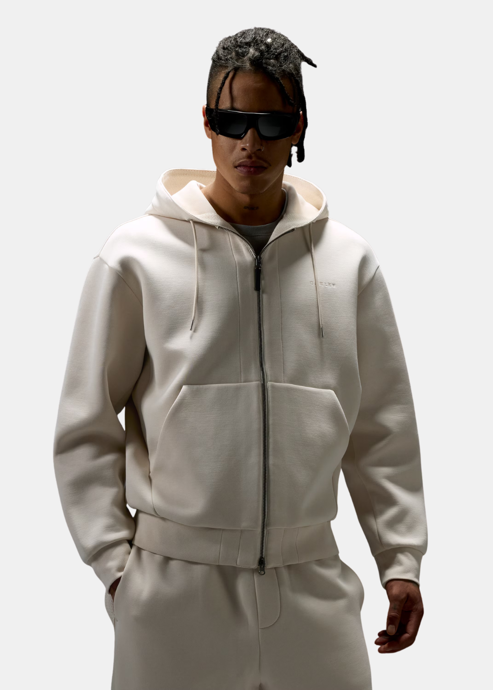 Homme de face portant le sweat zippé beige Oakley avec les mains dans les poches kangourou.