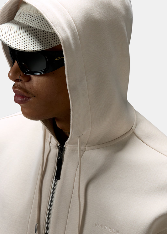 Gros plan porté sur la capuche du sweat beige Oakley, montrant la texture intérieure et les lunettes.