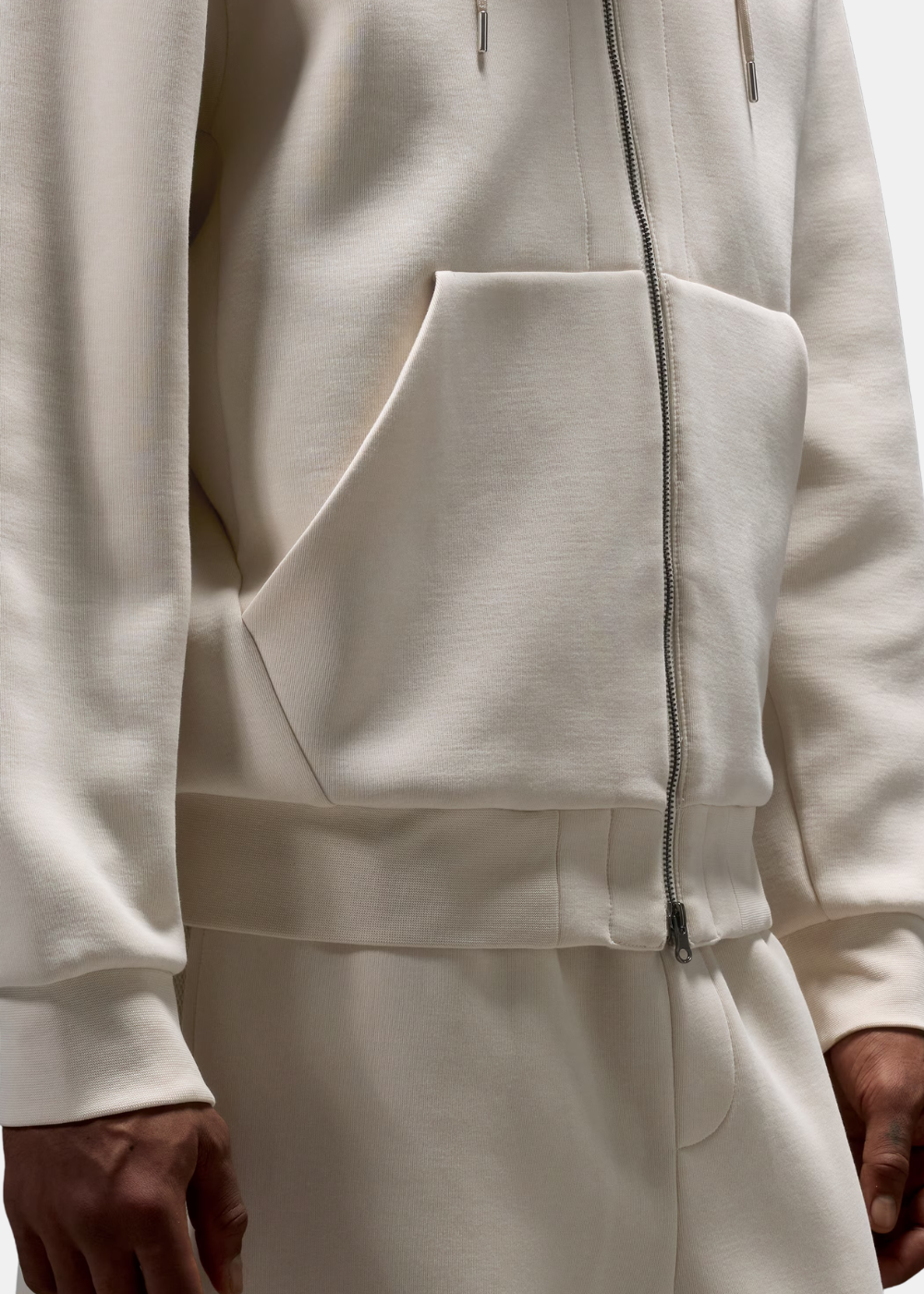 Zoom sur le bas du sweat zippé beige Oakley montrant la finition des poches et la taille élastiquée.