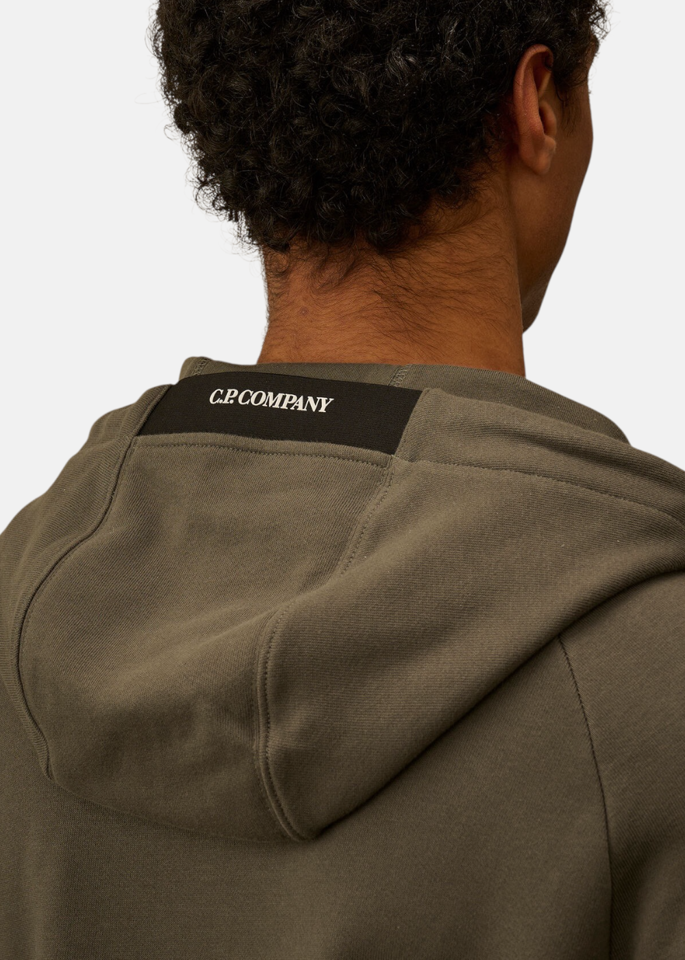 Gros plan de dos d'un mannequin portant la capuche ajustable du sweat kaki C.P. Company.