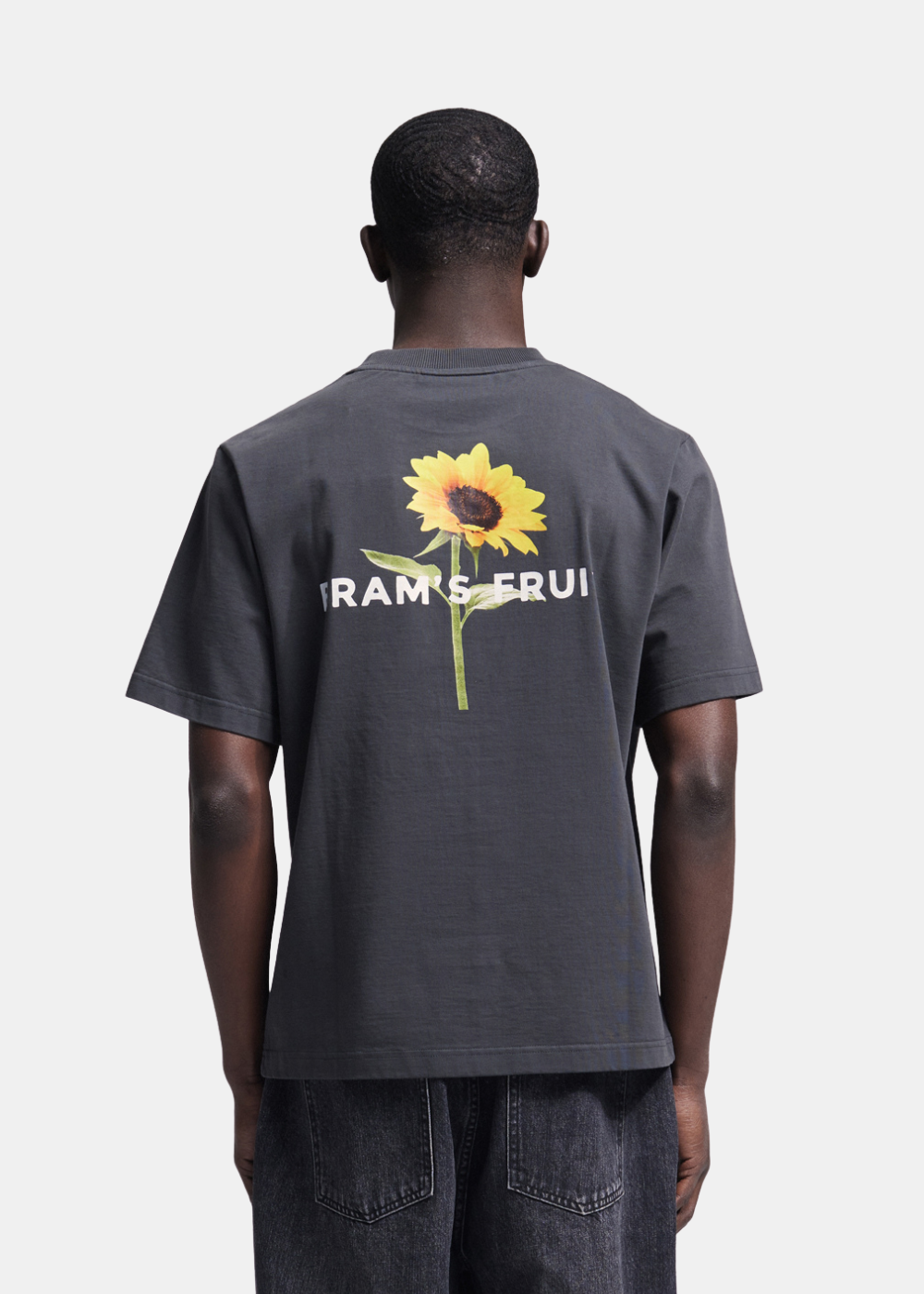 Homme de dos portant le t-shirt noir Shadow Black Bram’s Fruit Sunflower avec sérigraphie grand tournesol.