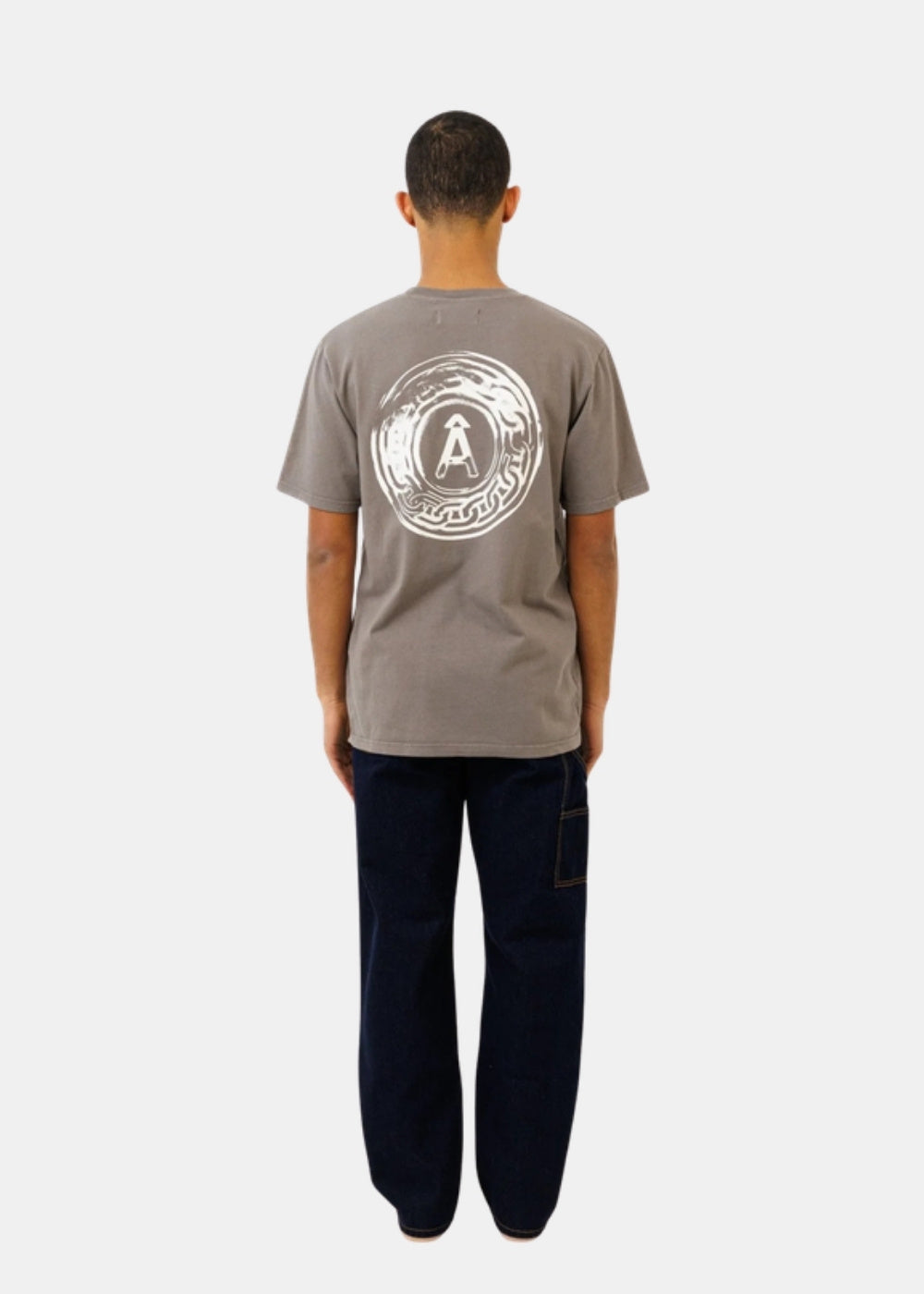 Porté de dos d'un t-shirt gris Ateliers de Nîmes AD AUGUSTA avec grand emblème circulaire sérigraphié sur le haut du dos.