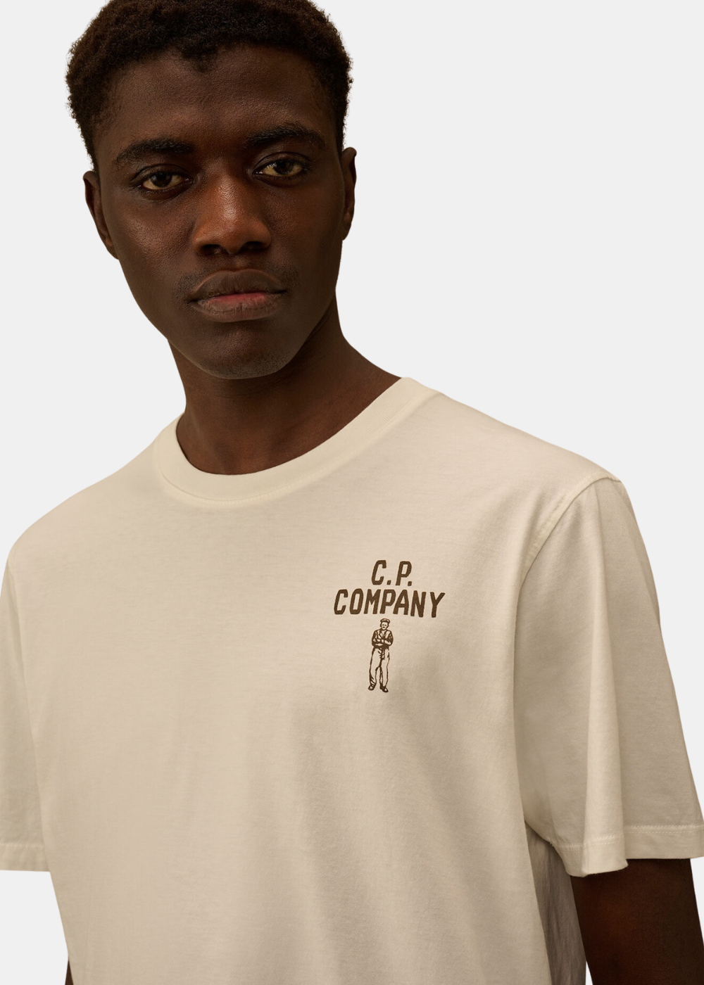Zoom sur le porté du t-shirt beige C.P. Company montrant le logo poitrine et l'illustration marin