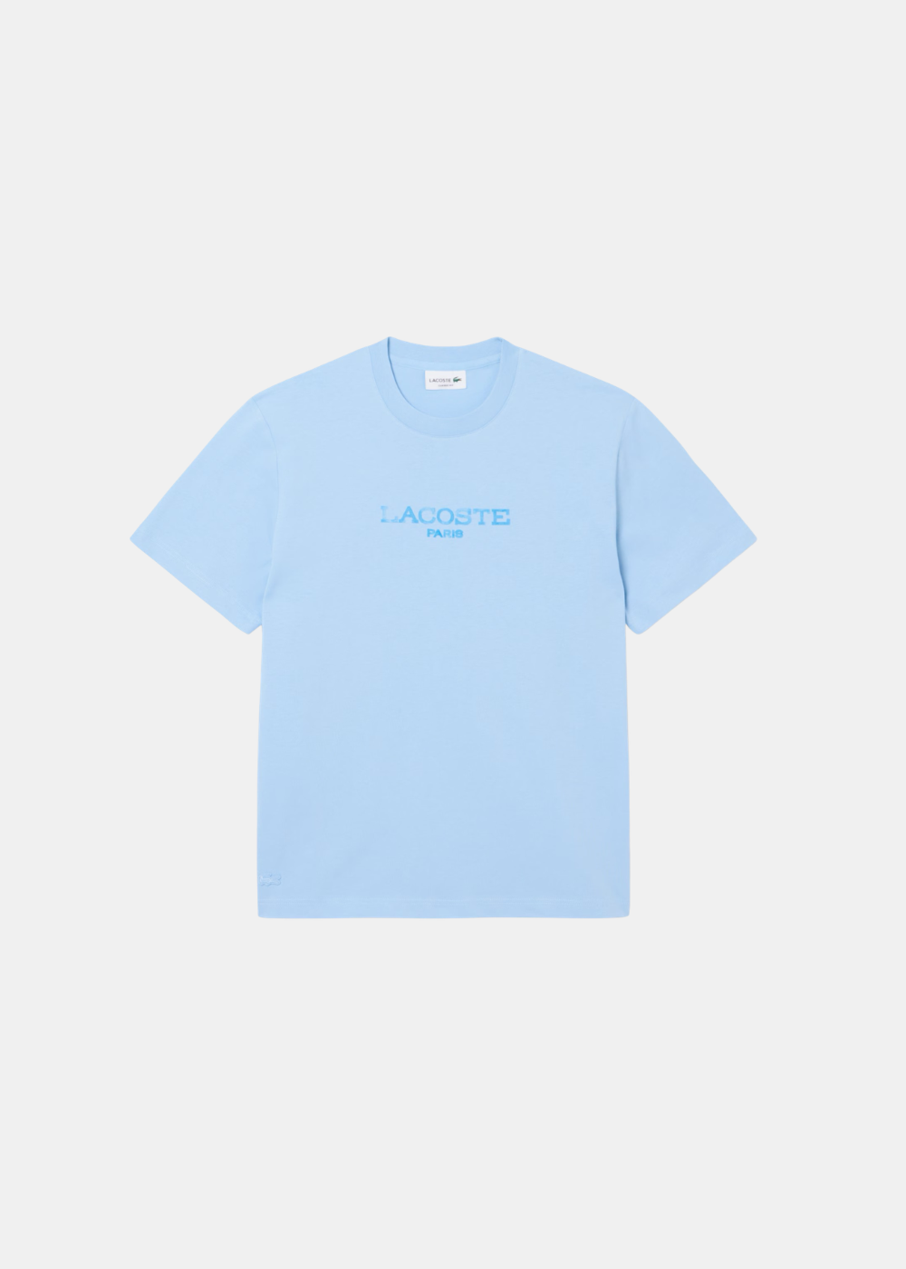 T-shirt Lacoste bleu ciel avec logo Lacoste Paris effet tampon sur la poitrine. Vue de face à plat sur fond gris clair.