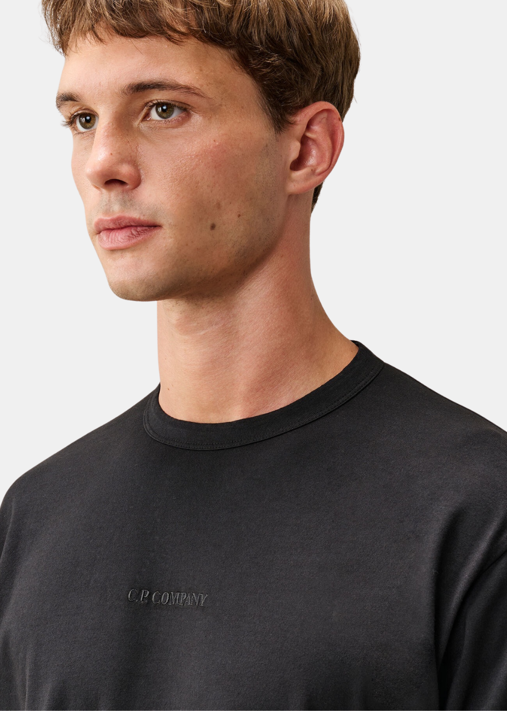 Gros plan sur le col rond et la broderie ton sur ton C.P. Company sur le t-shirt noir