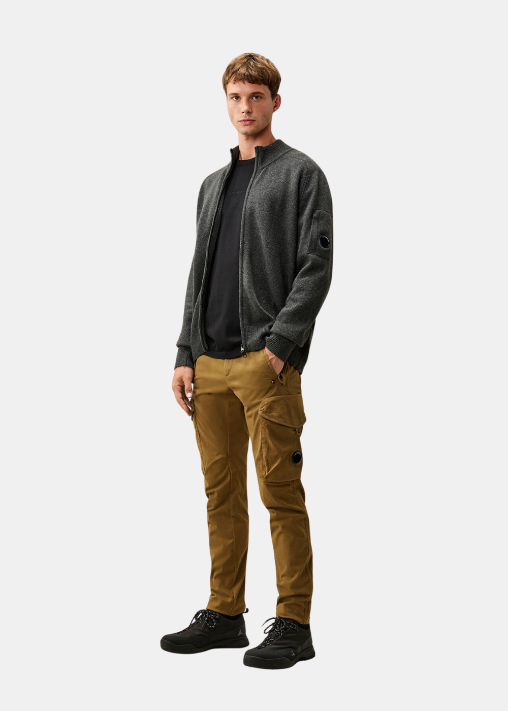 Silhouette portée du t-shirt noir C.P. Company sous un gilet zippé gris avec pantalon cargo camel