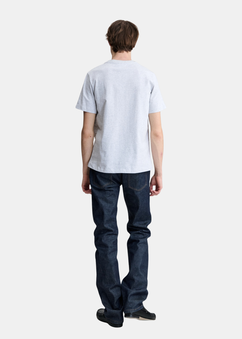 Look complet de dos montrant la coupe droite du t-shirt standard gris APC avec un jean brut bleu foncé