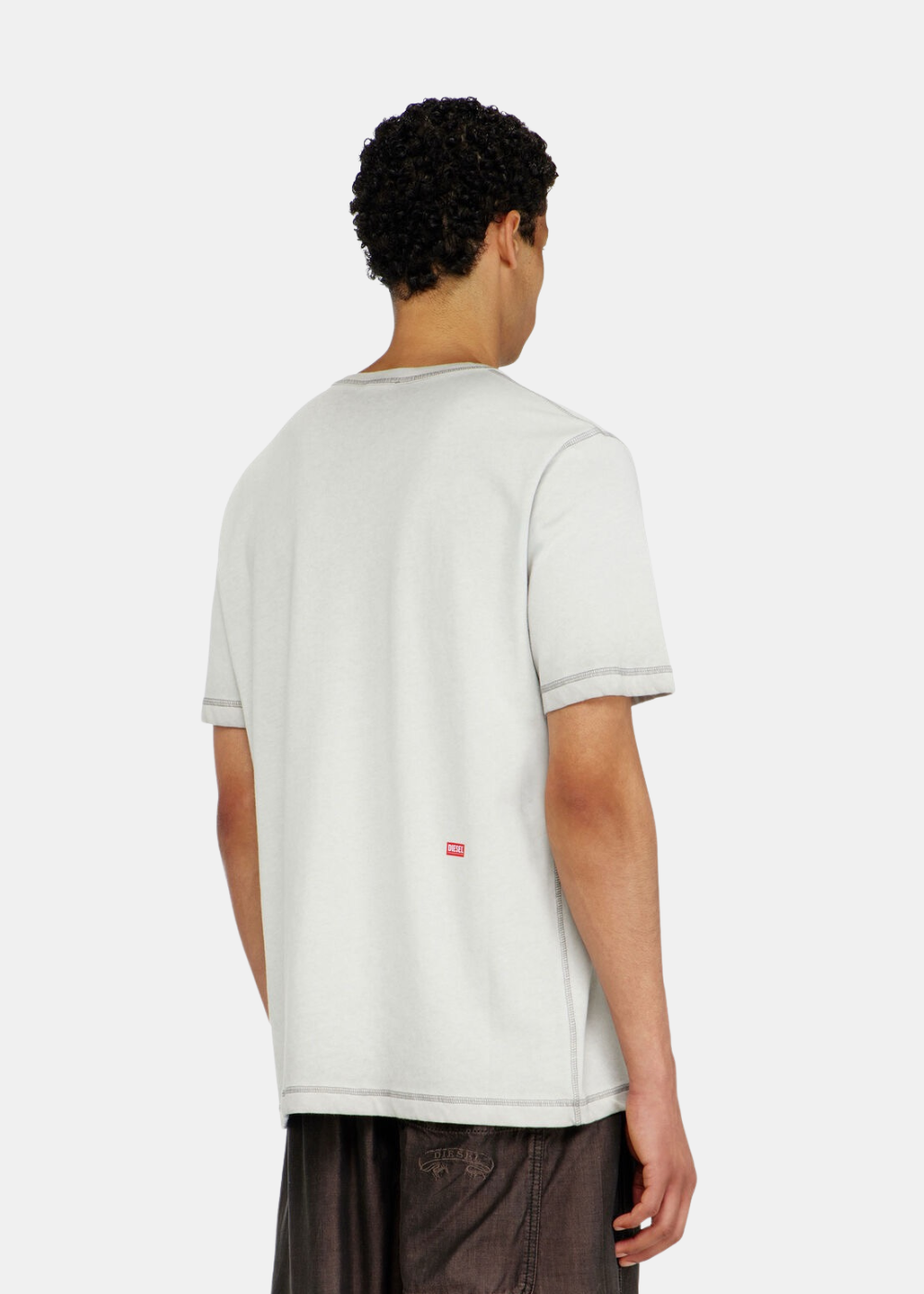 Vue arrière de trois-quarts du t-shirt gris clair Diesel montrant les coutures apparentes et un mini logo rouge.