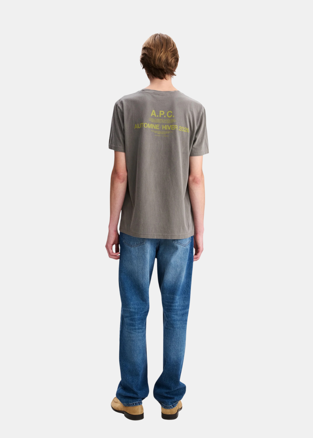 Mannequin homme de dos en pied portant le t-shirt gris délavé A.P.C. révélant l'imprimé sérigraphié jaune « A.P.C. AUTOMNE / HIVER 2026 » dans le haut du dos