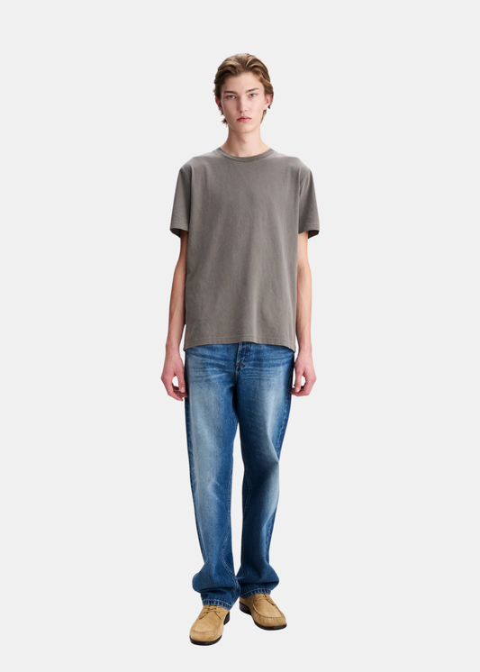 Mannequin homme de face en pied portant le t-shirt gris délavé A.P.C. avec un jean bleu délavé et des chaussures de ville en daim