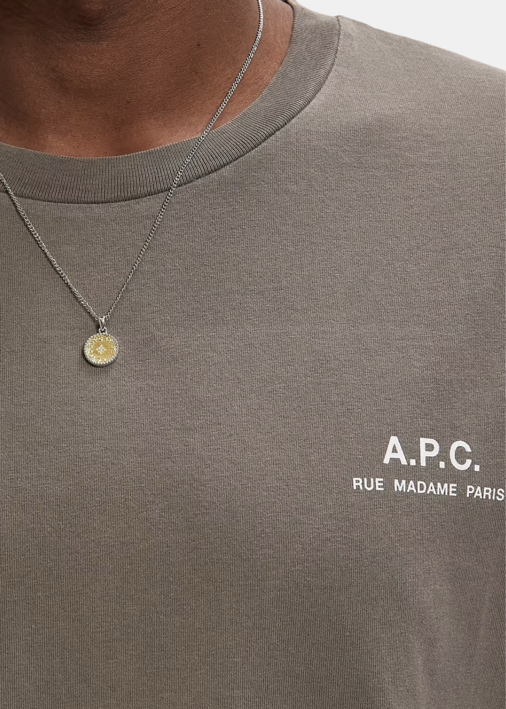 Gros plan sur l'imprimé sérigraphié blanc « A.P.C. RUE MADAME PARIS » sur la poitrine du t-shirt gris taupe avec détails des coutures du col