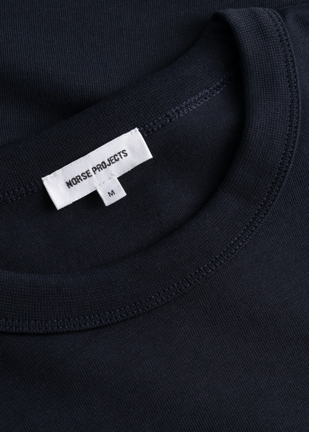Zoom sur le col rond et la texture du coton organique bleu marine du t-shirt Homme.
