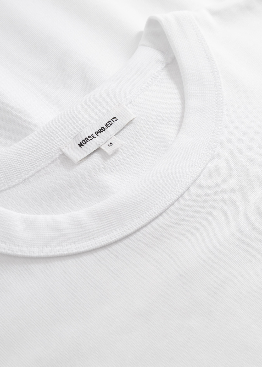 Zoom sur le col rond côtelé et la texture du coton organique du t-shirt Homme blanc.