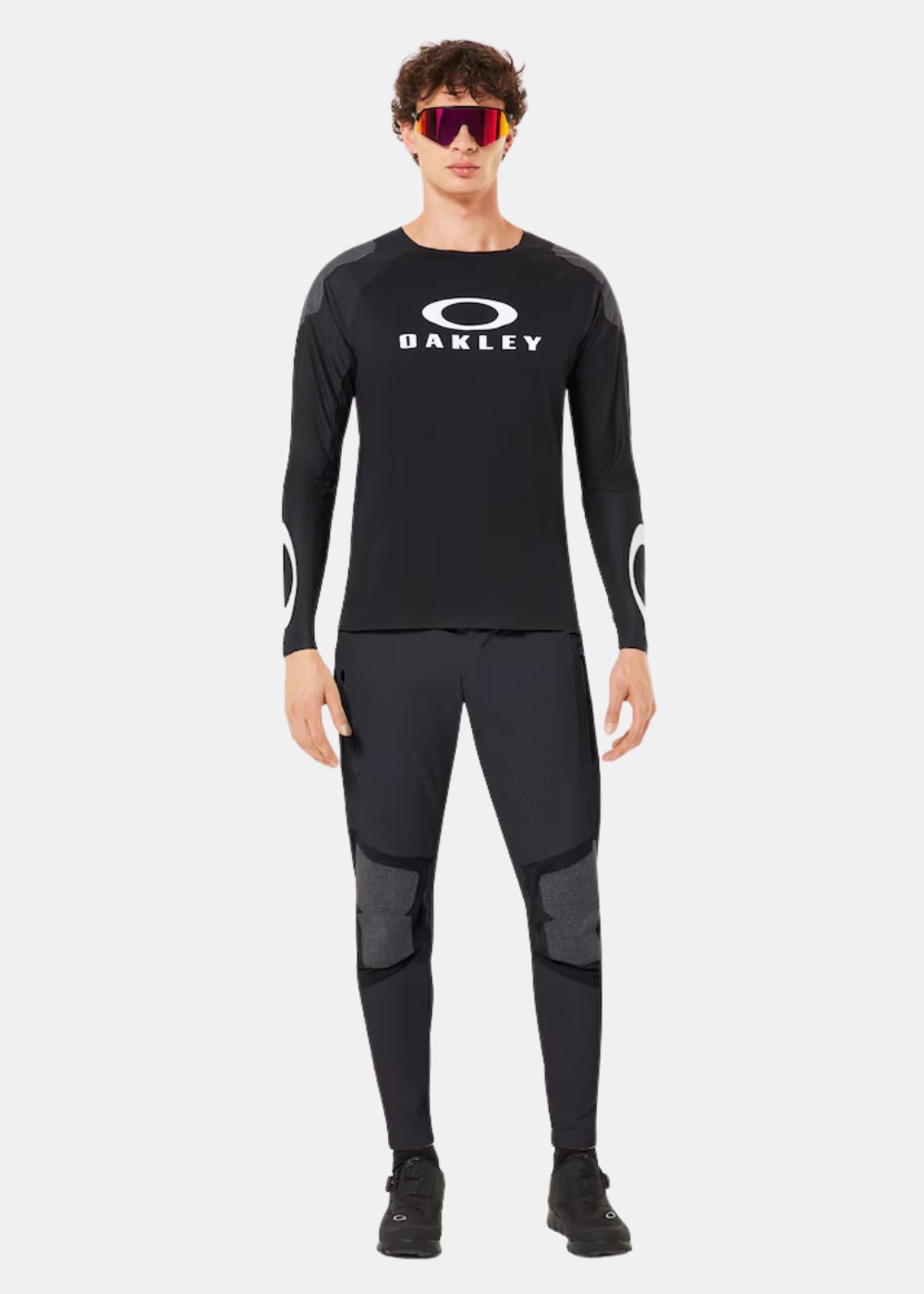 Mannequin de face portant le t-shirt Oakley noir, un pantalon technique et des lunettes de soleil