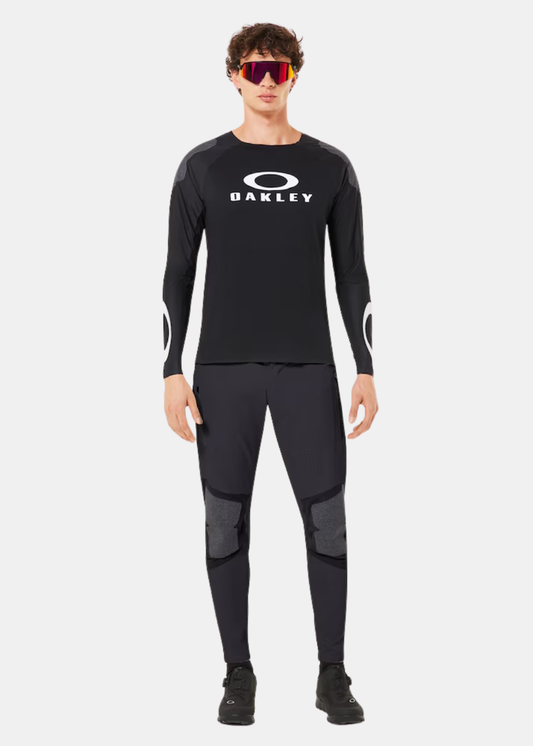 Mannequin de face portant le t-shirt Oakley noir, un pantalon technique et des lunettes de soleil