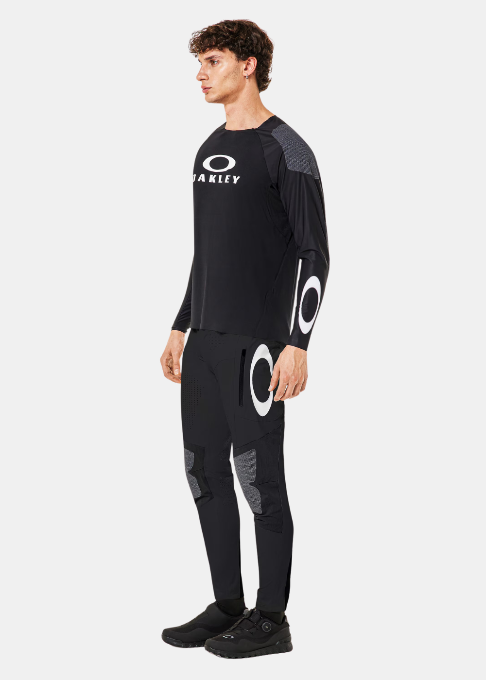 Vue de profil d'un mannequin portant le look complet Oakley technique noir avec lunettes de soleil