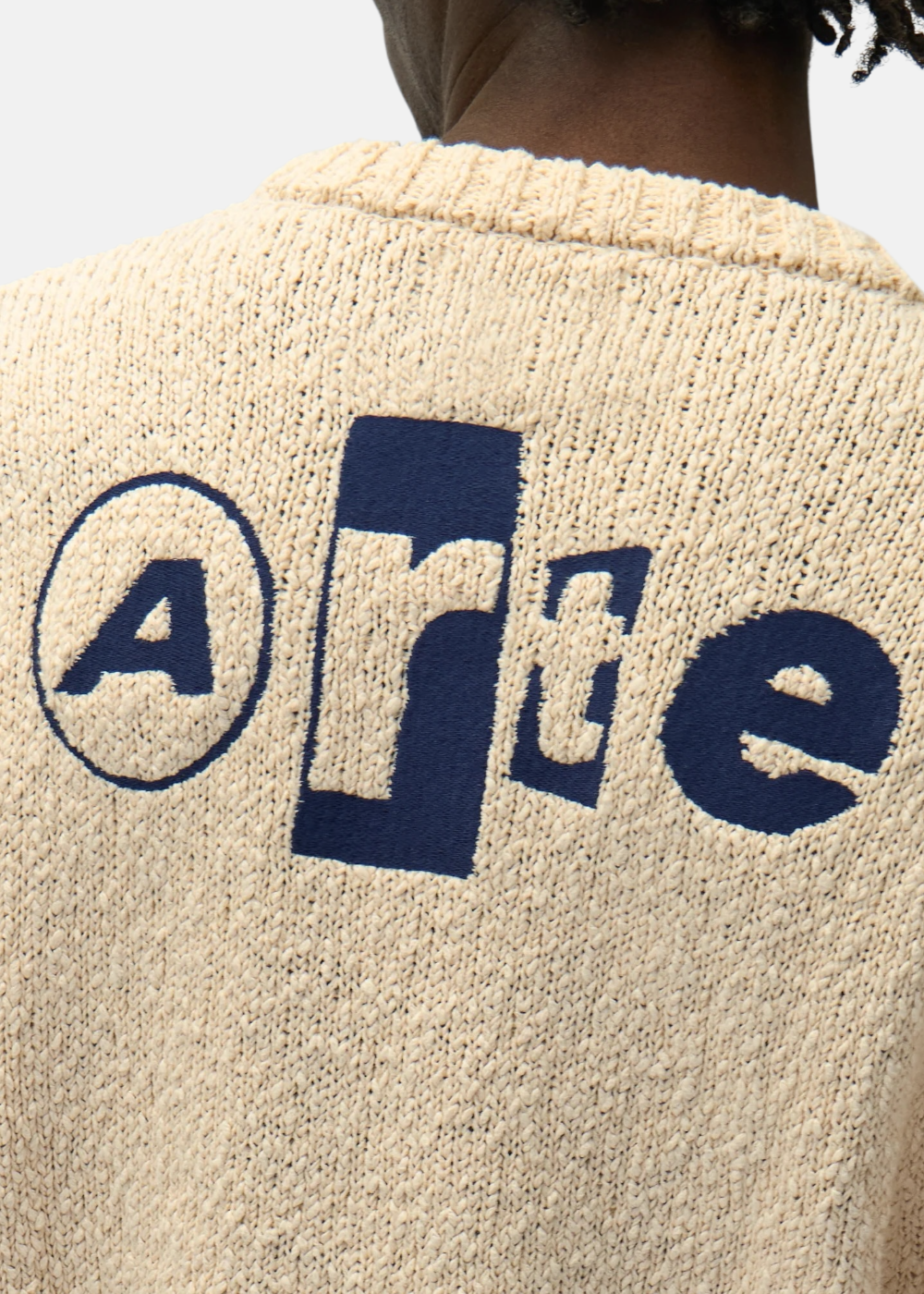 Gros plan sur le dos d'un t-shirt en maille beige Arte Antwerp avec logo bleu brodé en relief.
