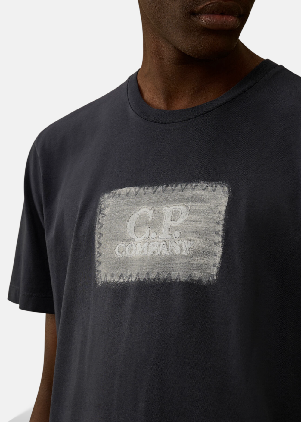Gros plan sur la texture du logo C.P. Company brossé à la main et les coutures du col du t-shirt