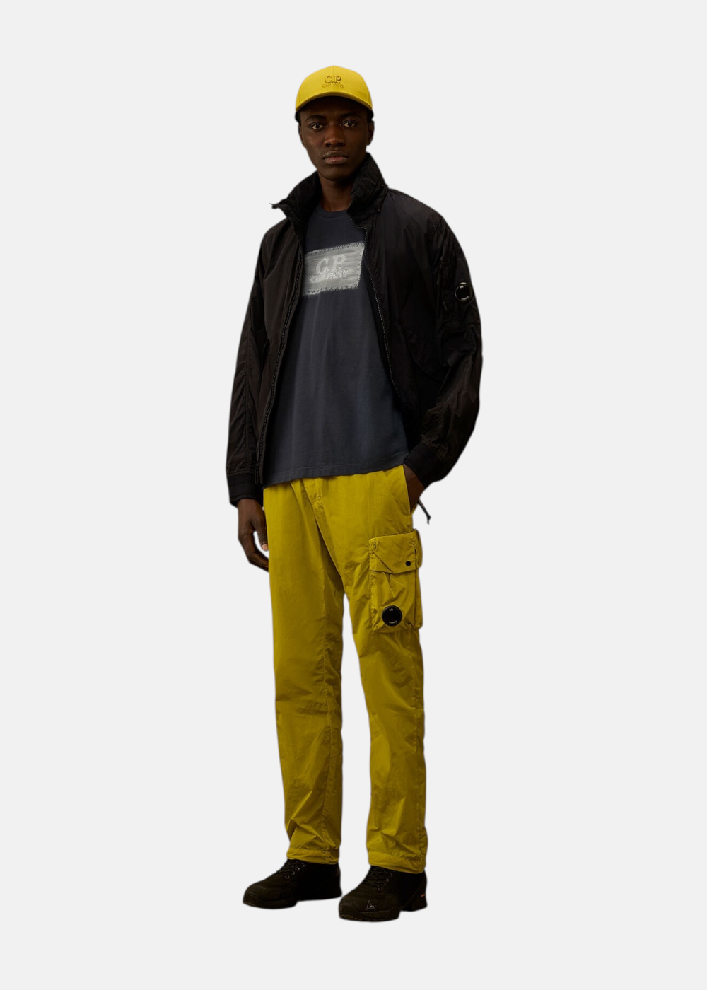 Silhouette complète avec t-shirt marine, veste noire, pantalon cargo jaune et casquette assortie