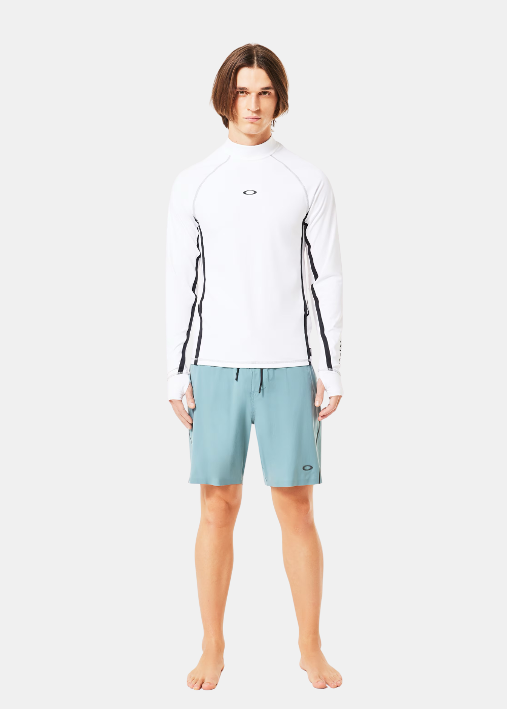 T-shirt de surf à manches longues blanc Oakley porté par un mannequin de face, associé à un short de bain bleu clair.
