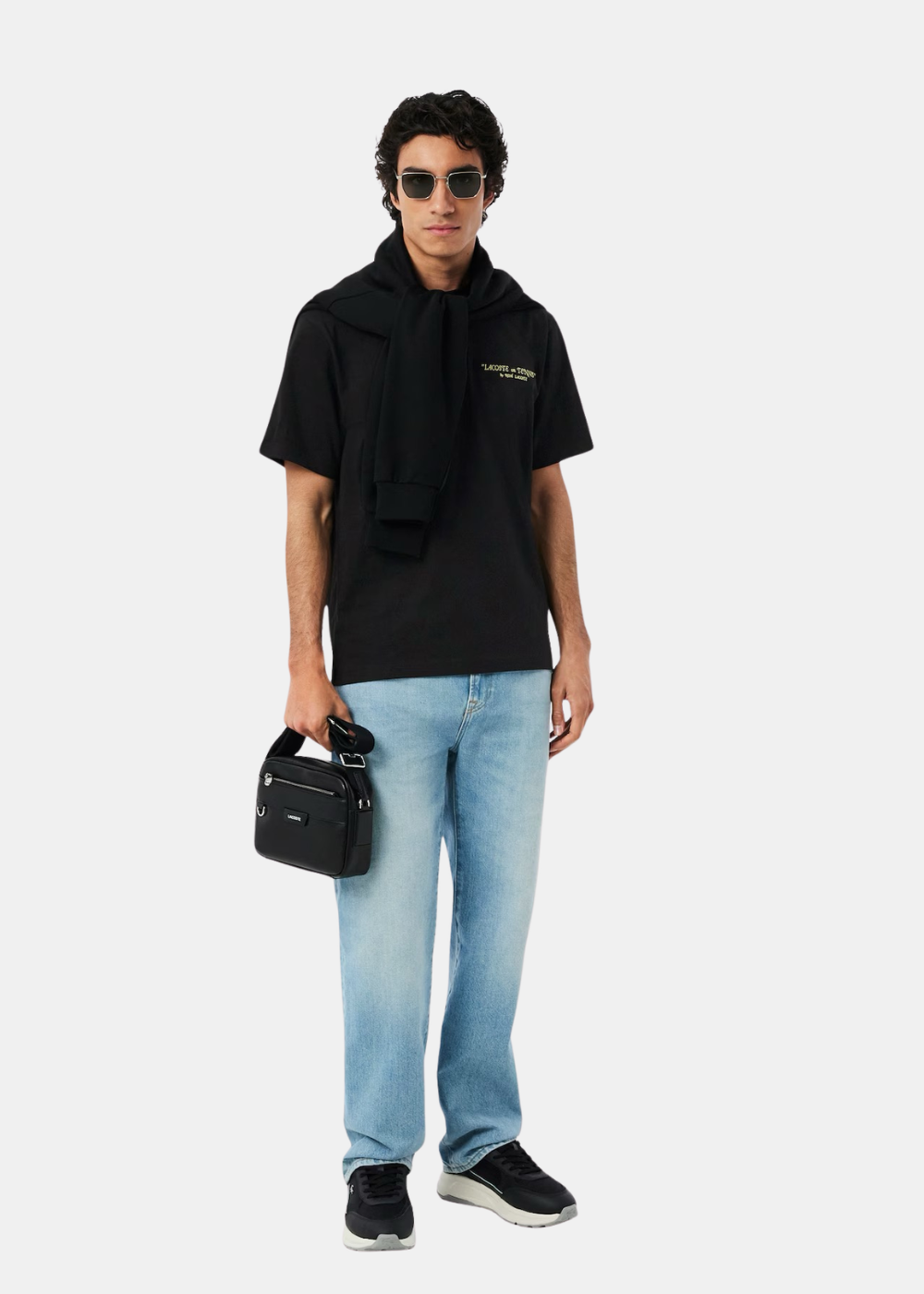Mannequin de face portant le t-shirt noir Lacoste avec un jean bleu.