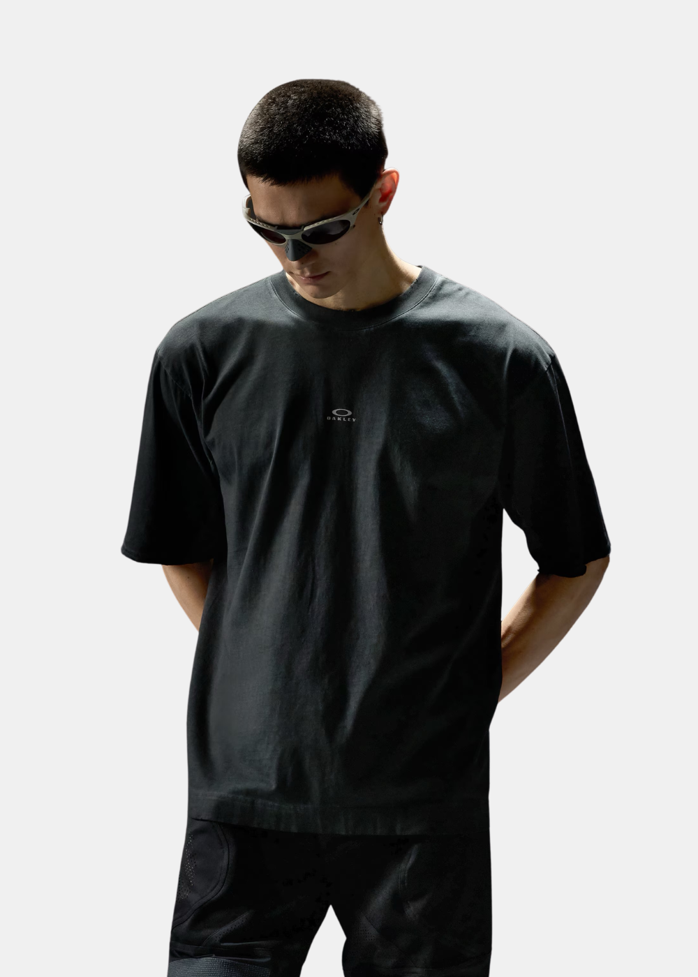T-shirt Oakley noir à coupe relax portée de face avec un pantalon technique assorti.