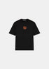 T-shirt noir Stone Island Compass Coordonnées en coton avec le logo boussole emblématique imprimé en orange au centre de la poitrine, présenté à plat de face.