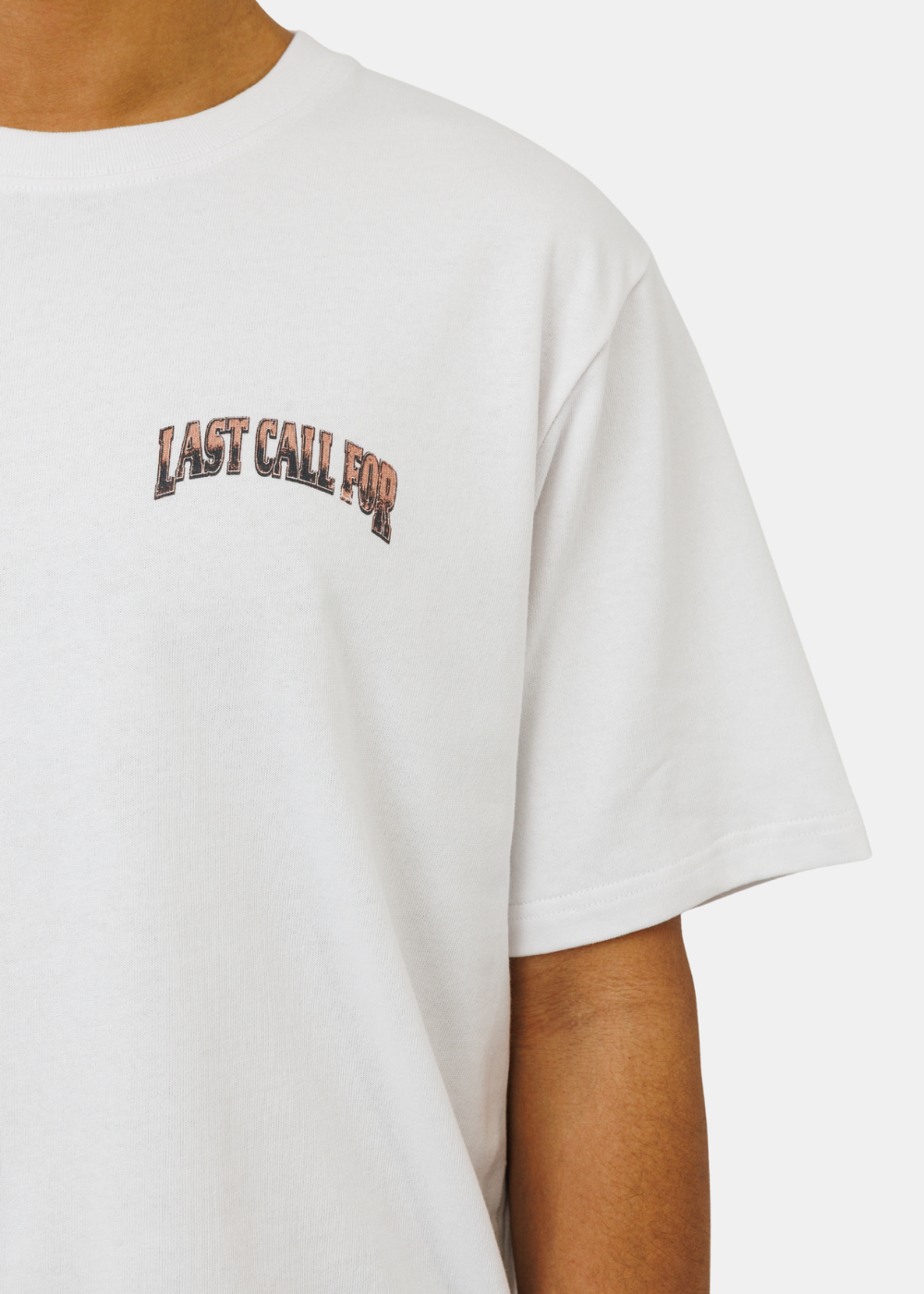 Zoom sur le petit logo Last Call For à l'effet usé imprimé sur la poitrine du t-shirt blanc