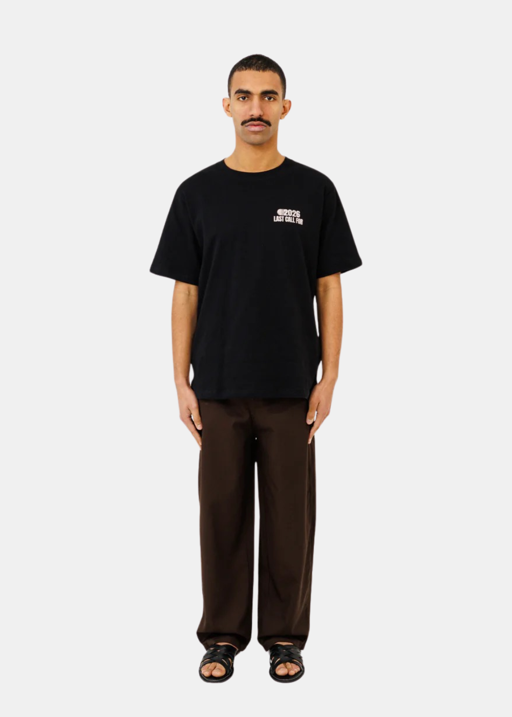 Mannequin portant le t-shirt noir Last Call For avec un pantalon marron et des sandales