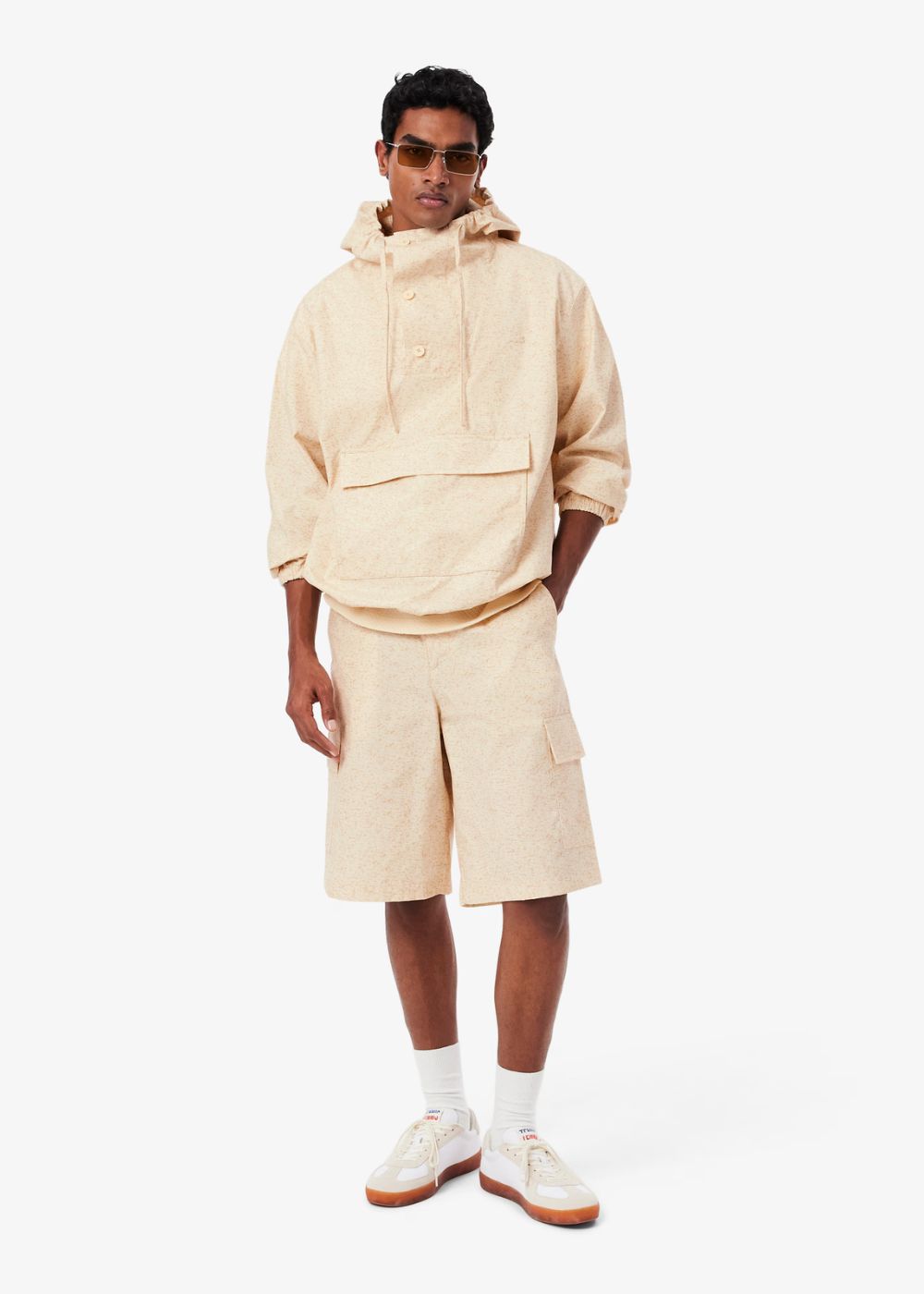 vue de face d'un mannequin debout habillé du Short cargo Lacoste beige imprimé et de sa veste enfilable