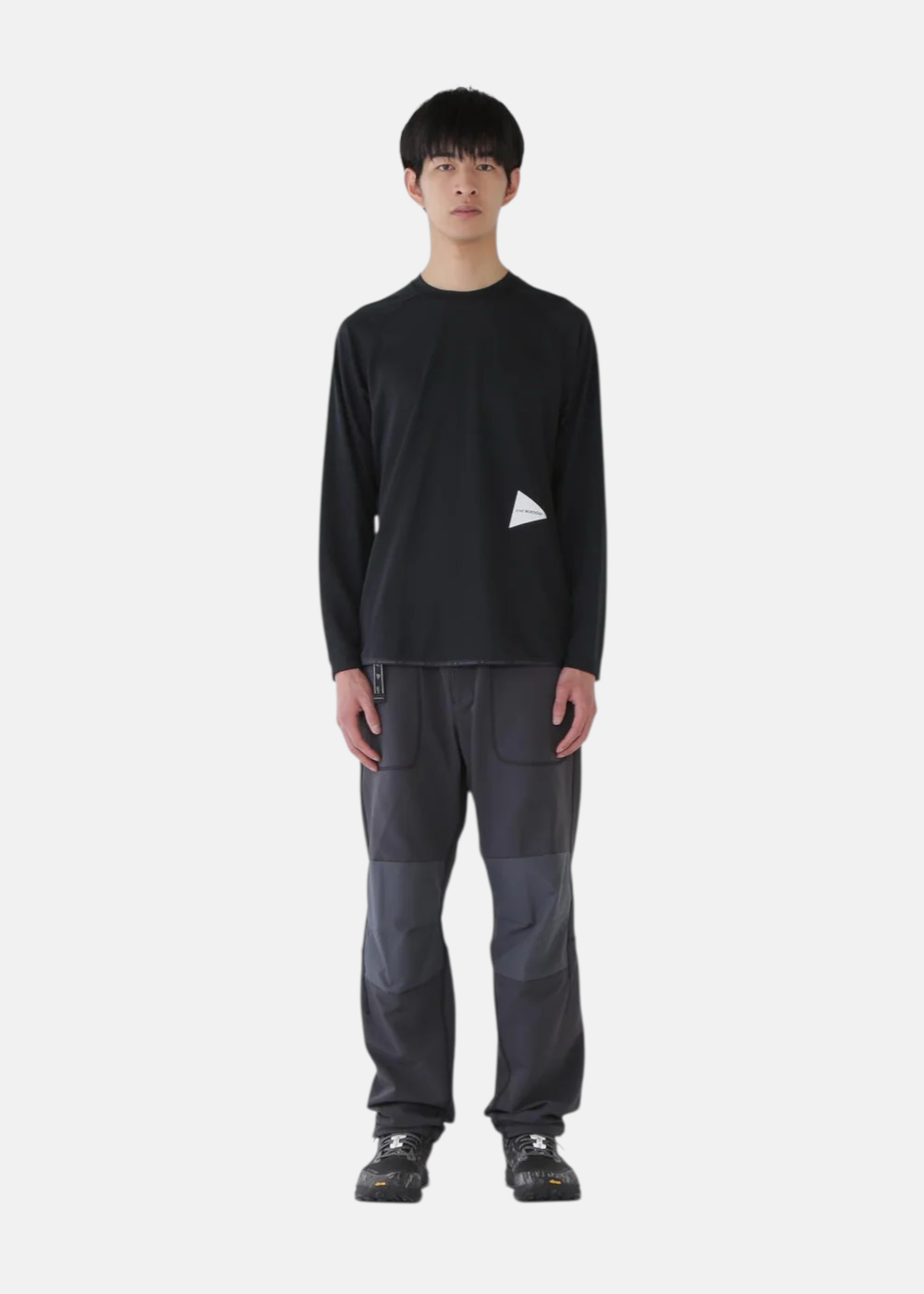 Homme de face portant le T-shirt manches longues technique And Wander noir.