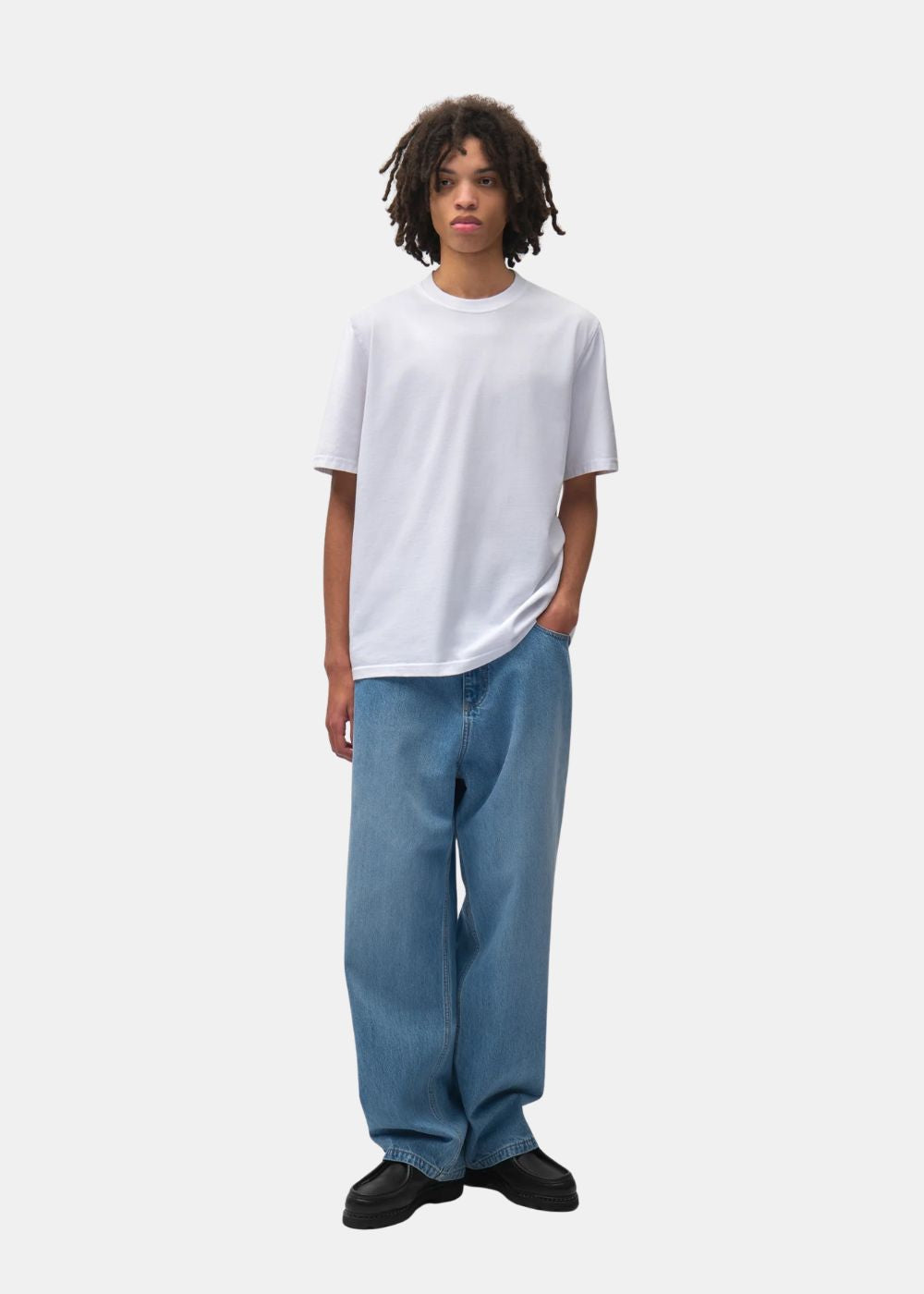 Vue de face du t-shirt Arte Antwerp blanc col rond porté avec un jean bleu basique.