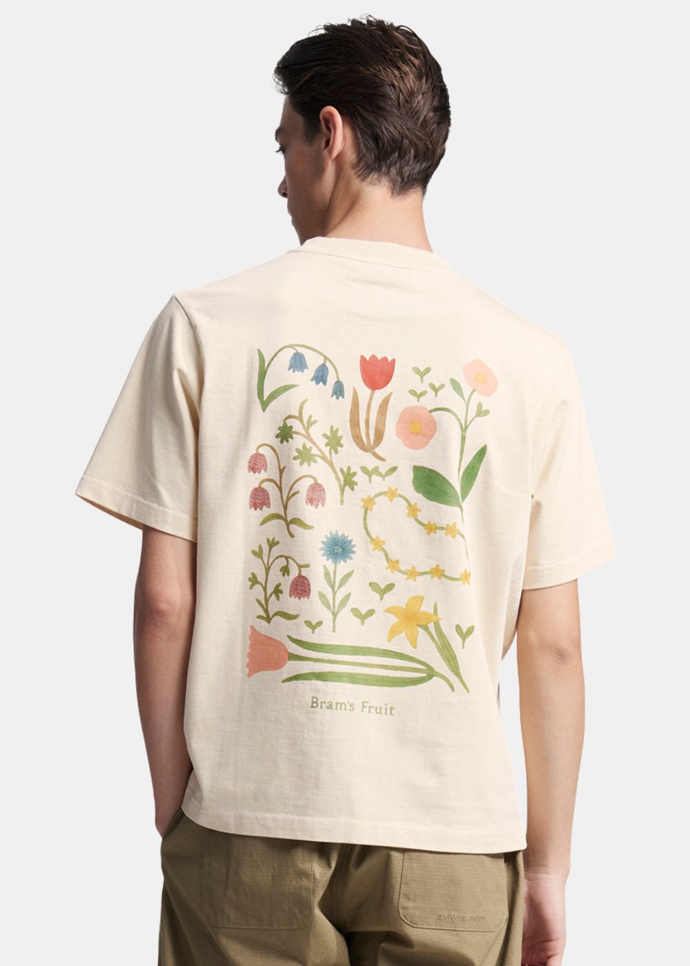 Vue de dos du t-shirt beige montrant l'imprimé artistique composé de plusieurs fleurs colorées réparties sur le coton lourd.
