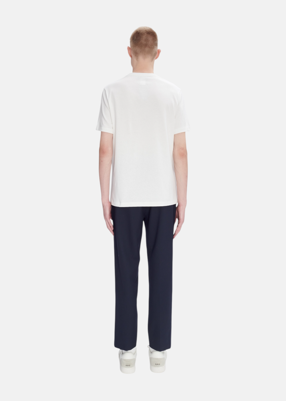 Silhouette complète avec t-shirt blanc A.P.C., jean brut bleu et chaussures de ville minimalistes.