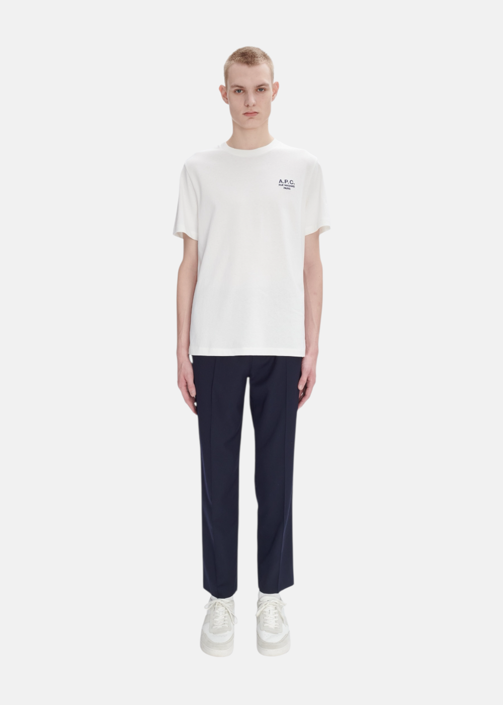 Silhouette complète avec t-shirt blanc A.P.C., jean brut bleu et chaussures de ville minimalistes.