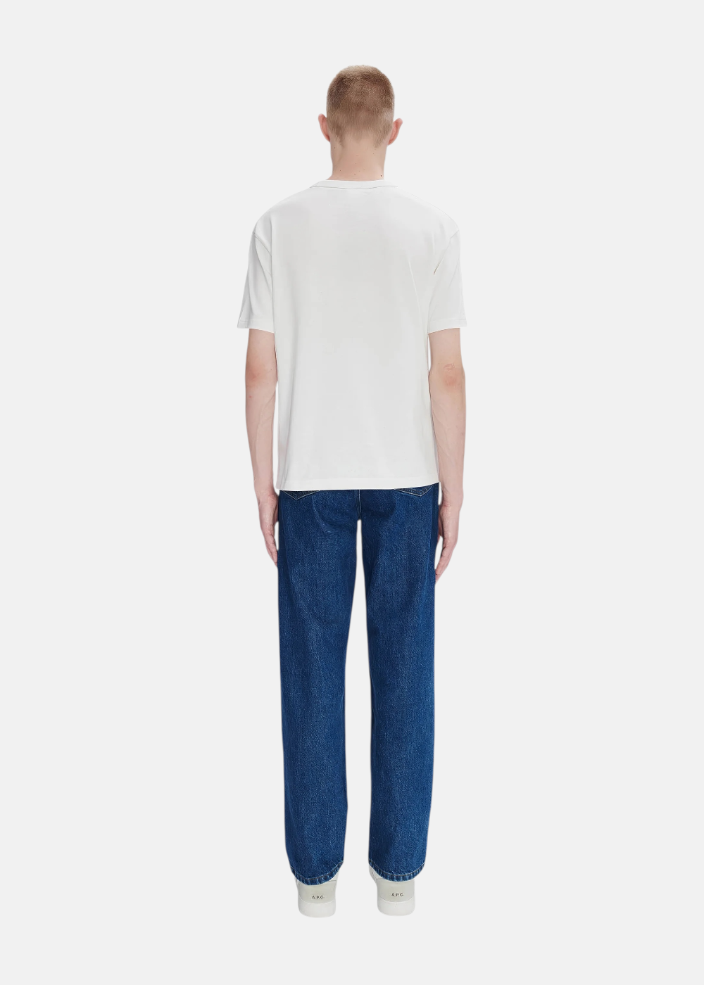 Silhouette complète avec t-shirt boxy blanc A.P.C., pantalon en toile bleu marine et baskets blanche.