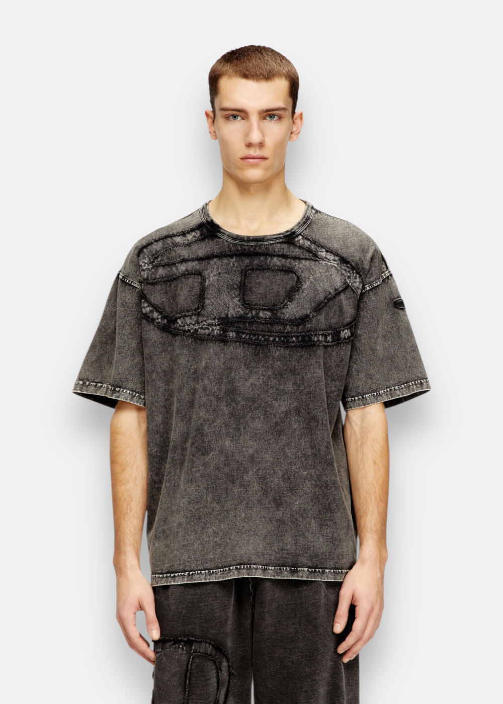 Homme portant le T-shirt Diesel délavé, logo D oversize sur la poitrine, style usé.