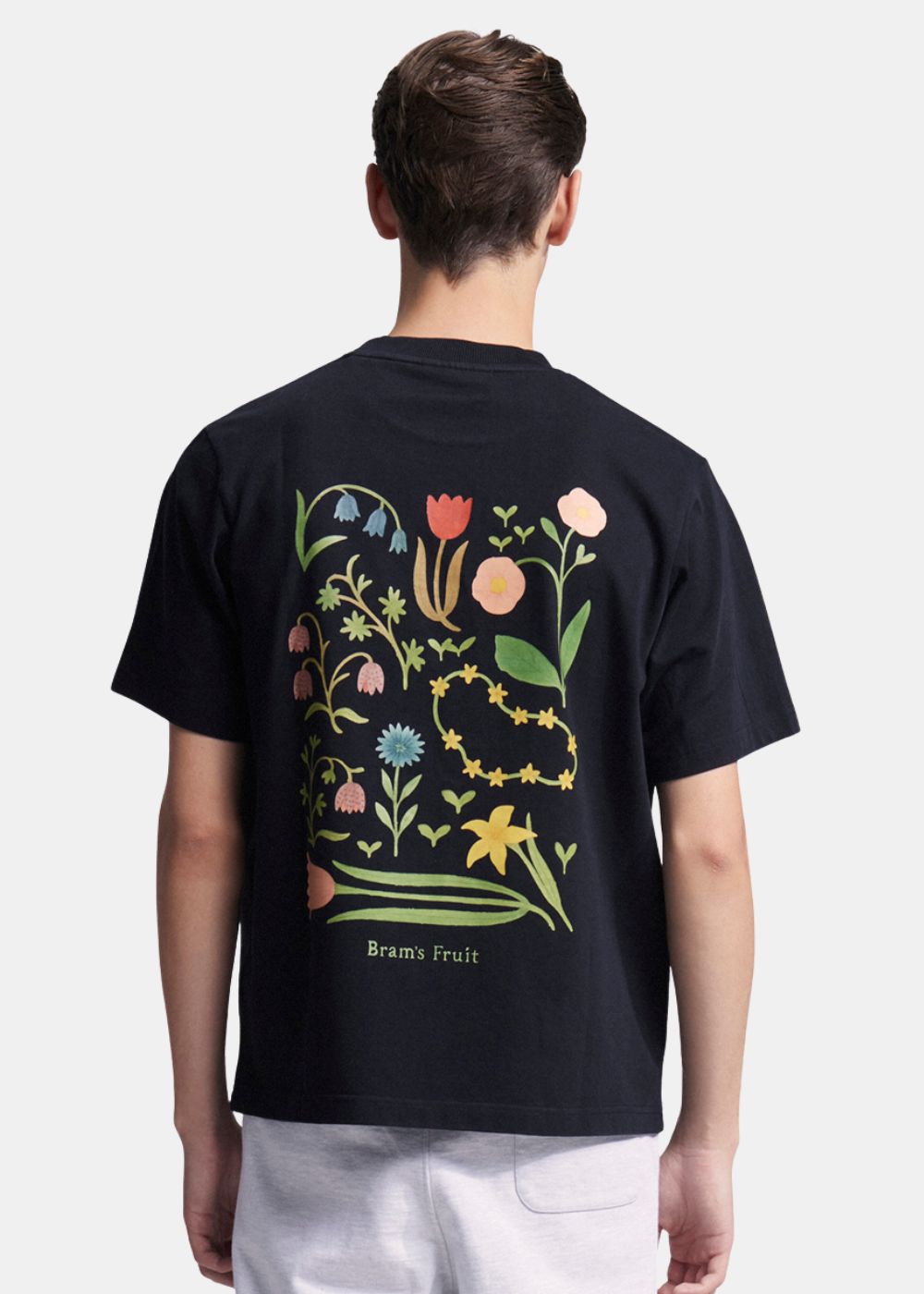 Vue de dos du t-shirt dévoilant un large imprimé artistique composé de plusieurs fleurs colorées aux détails botaniques.