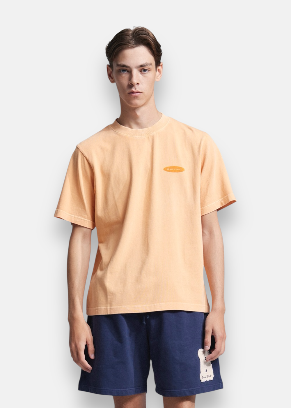 Homme portant de face un t-shirt orange délavé Bram's Fruit avec petit logo ovale sur la poitrine.