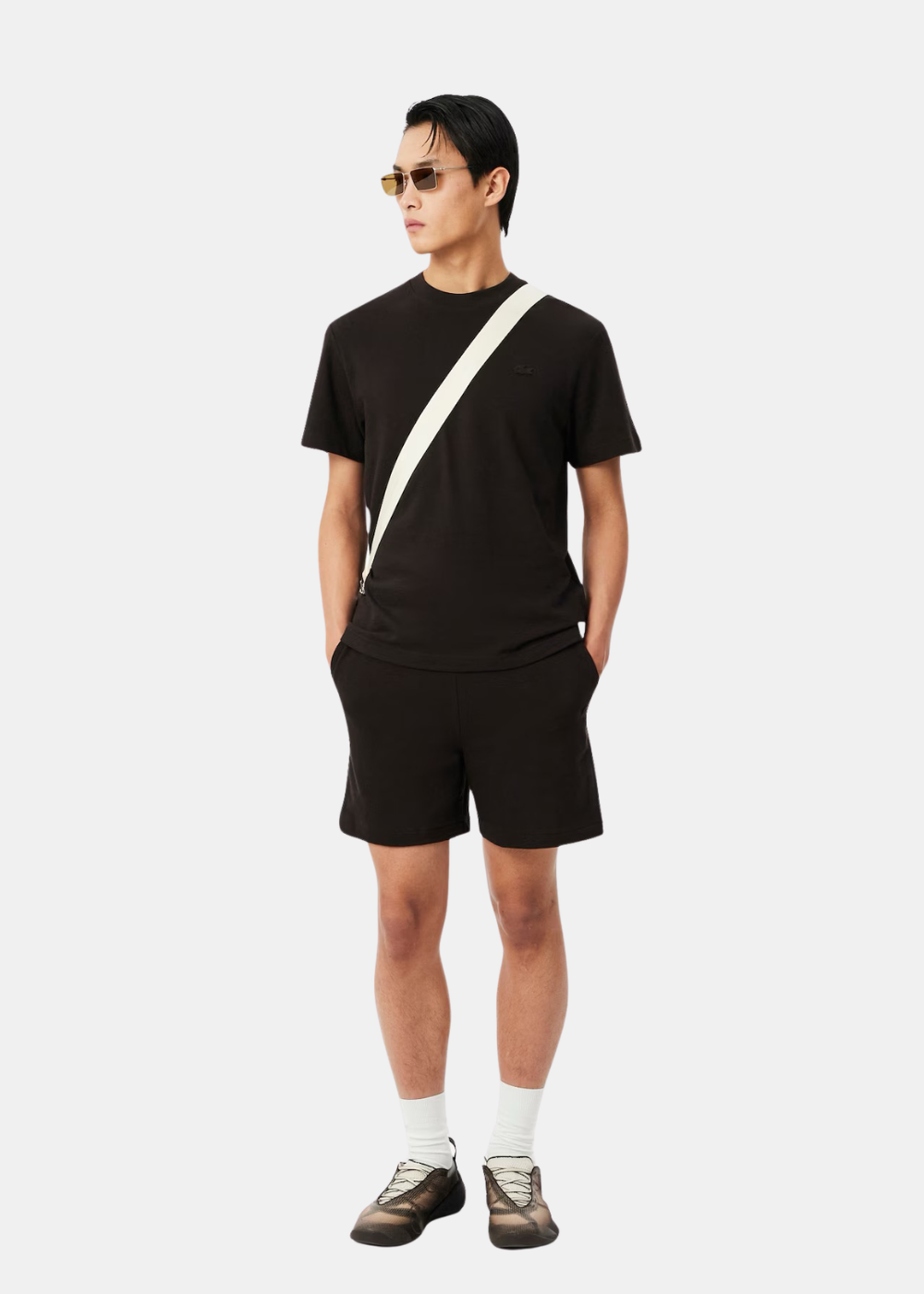 Homme portant un t-shirt porto Lacoste, short noir et accessoires, vue de face look complet.