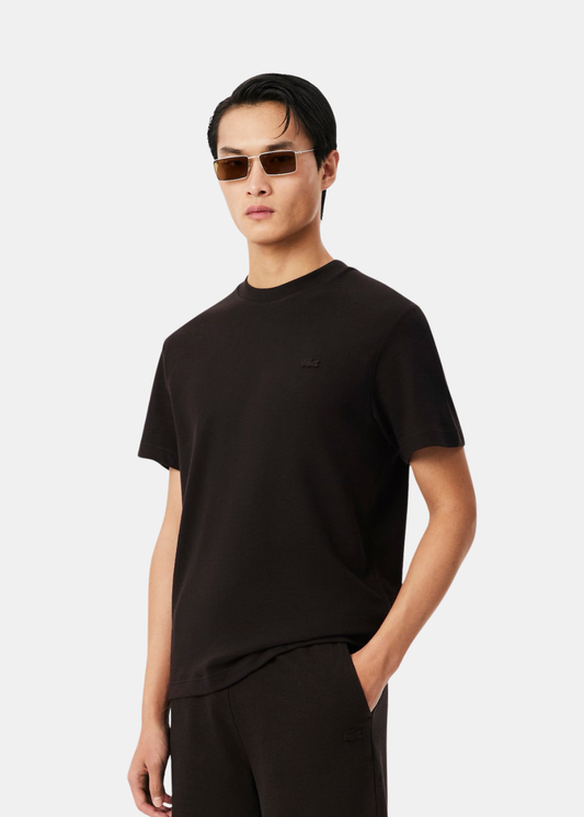 portrait d'un homme portant le t-shirt porto Lacoste col rond, vue de trois-quarts face.