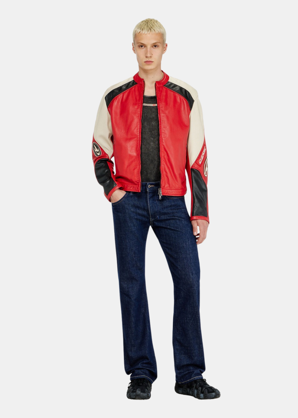Silhouette entière d'un mannequin portant la veste de cuir rouge Diesel ouverte sur un débardeur gris foncé, associée à un jean brut ajusté et des baskets noires texturées
