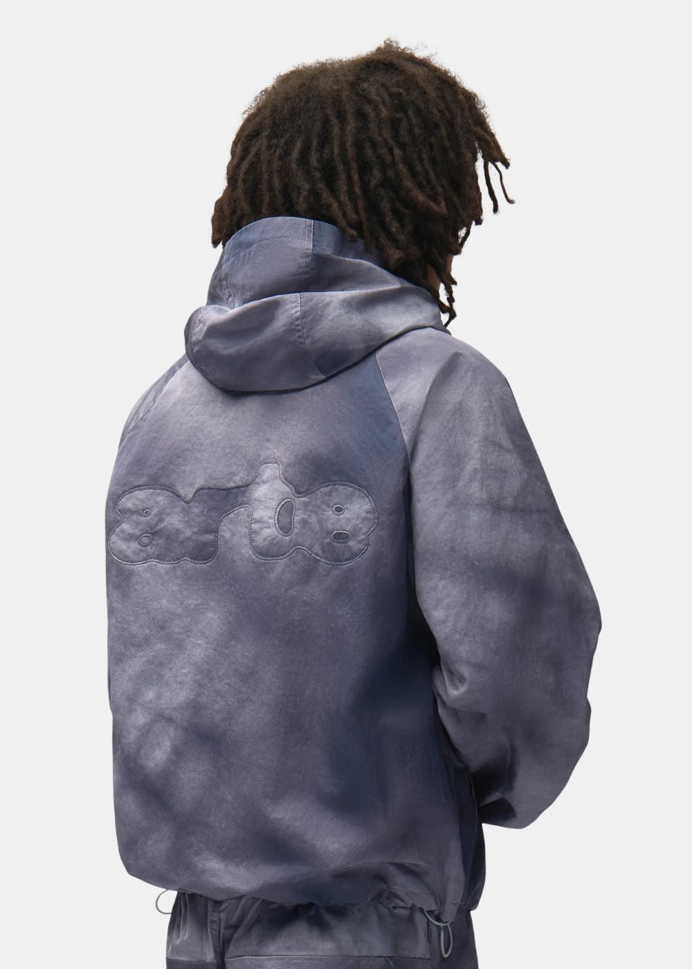 Zoom porté sur le dos de la veste Arte bleu gris mettant en valeur la capuche et le logo Arte grand format en relief.