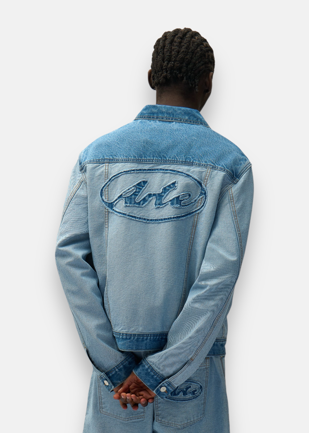 Dos d'une veste en denim inversée bleu clair Arte Antwerp avec grand logo signature au fini vieilli.