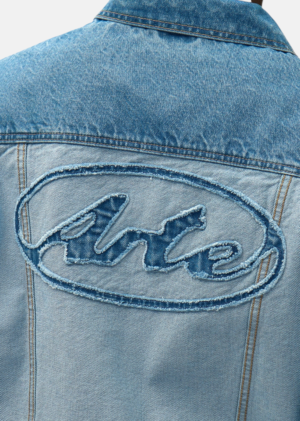 Gros plan sur la texture du denim bleu clair et les détails de construction inside out de la veste Arte Antwerp.