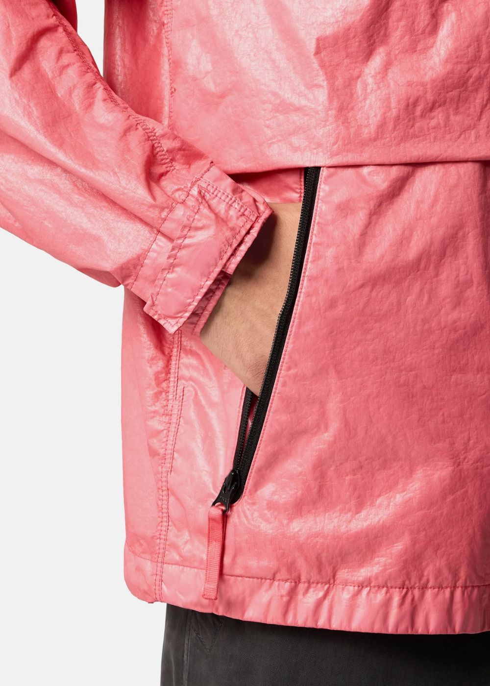 Gros plan sur la poche latérale zippée noire et la manche ajustée d'une veste légère rose Stone Island 3L TC.